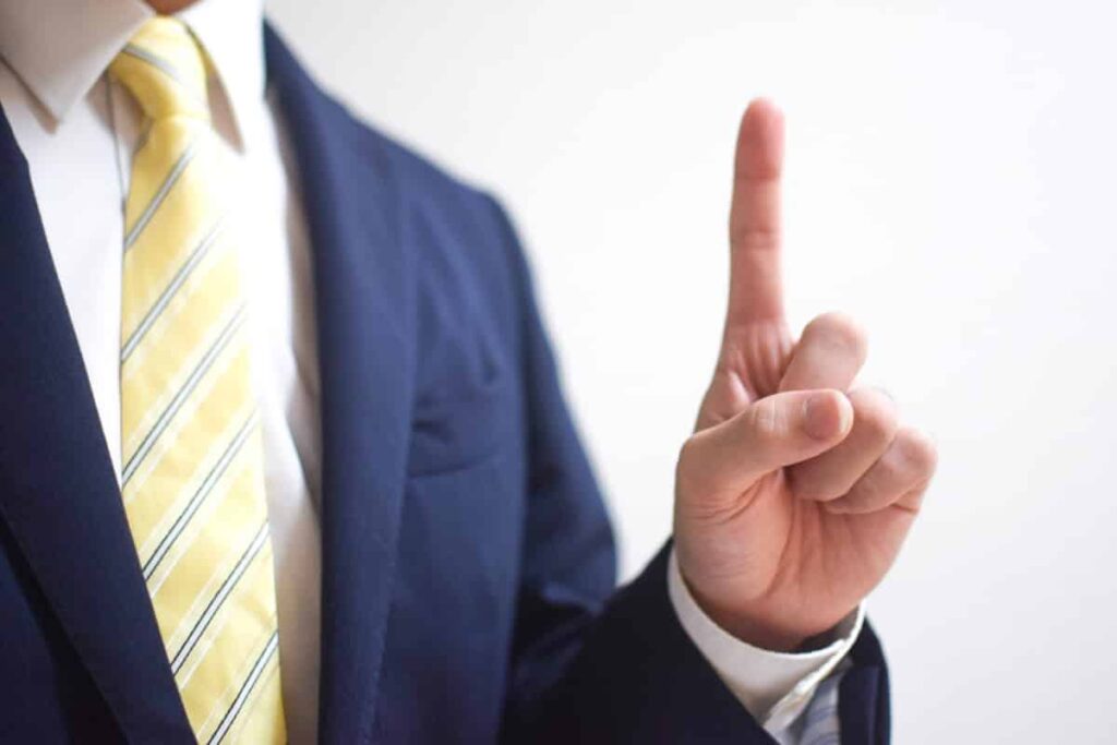 人差し指を立てるスーツ姿の男性